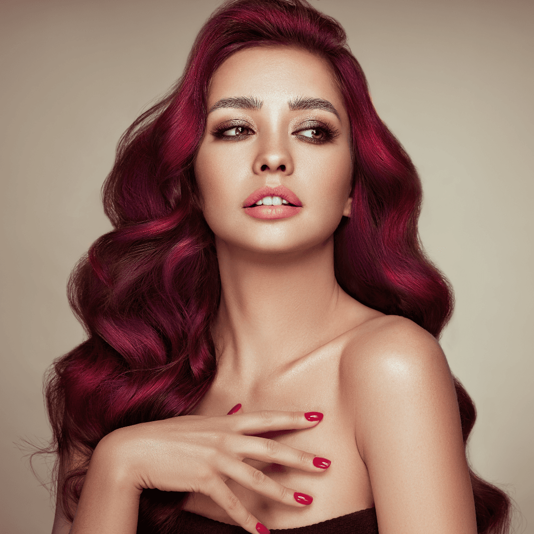 Woman with long, voluminous hair coloured in rich red and violet tones, styled in soft waves – professional hair colouring at Merluza Hair & Beauty, Hall Green, Birmingham.